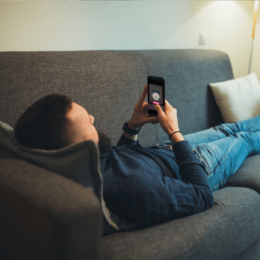 Mann, der sich auf einer Couch entspannt und mobile Spiele spielt