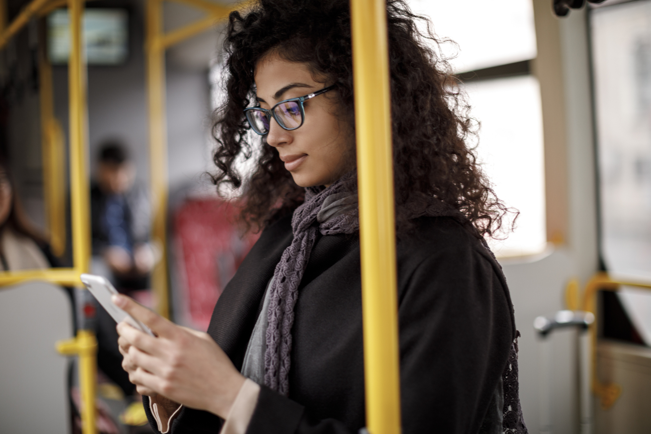Woman commuting on a bus while looking at her phone.
