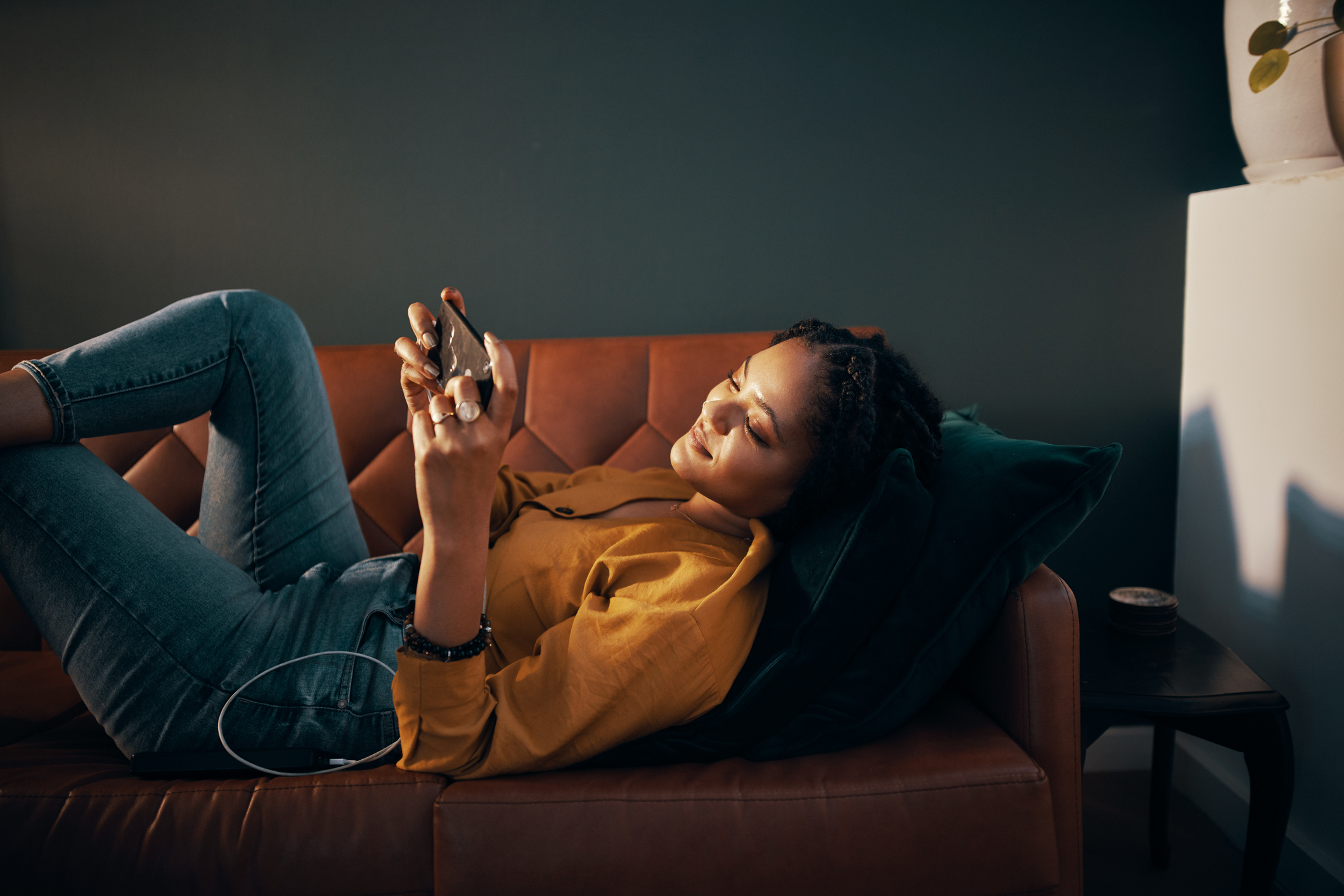 Une femme jouant à un jeu mobile sur un canapé