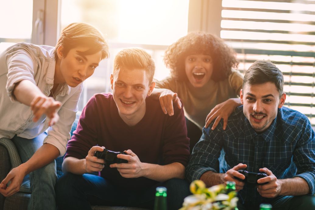 Four friends playing video games and smiling