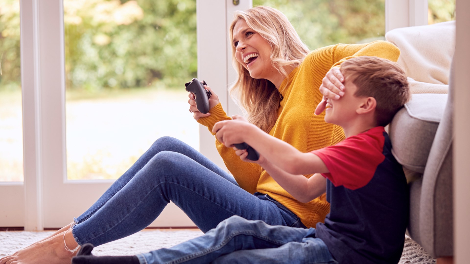 A mom and her son laugh while playing video games together.