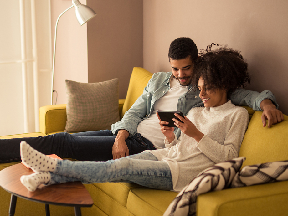 Una coppia si rilassa sul divano giocando a giochi mobile